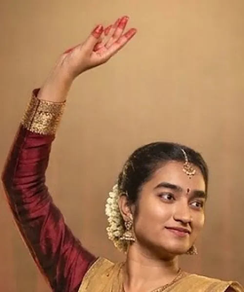 Ashmitha's raised hand held in a hastak, alta-painted fingers curved